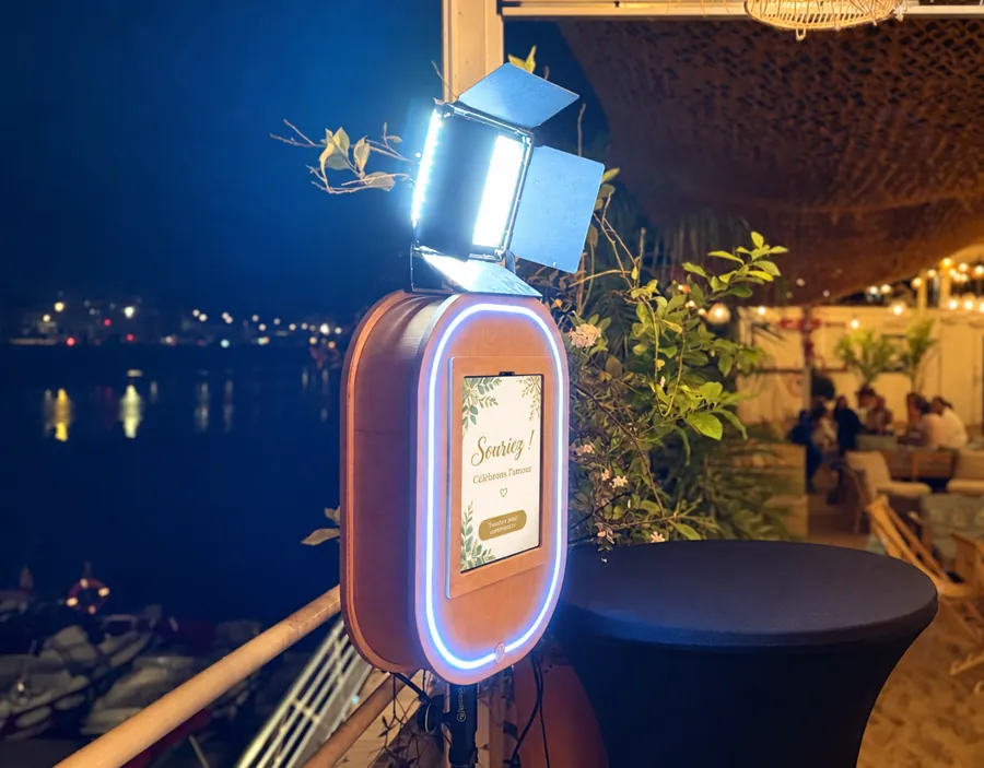 Photobooth en bois éclairé pendant une réception en extérieur