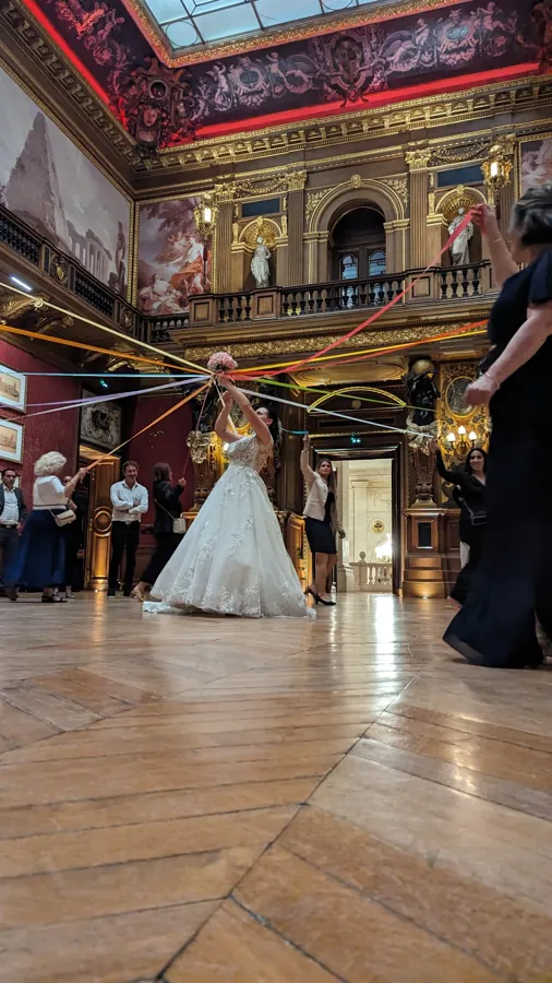 Une mariée entourée de ses invités dans une salle de réception ornée
